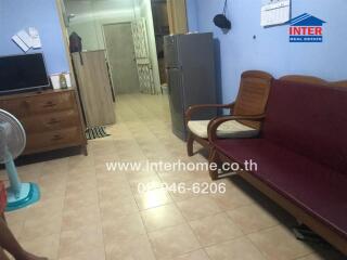 Spacious furnished living room with tiled flooring, comfortable seating, and essential appliances