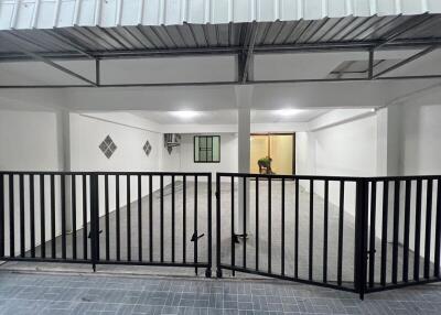 Spacious covered garage area with tiled flooring and secure metal gate