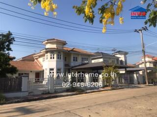 Two-story residential building in a suburban neighborhood with blooming yellow trees