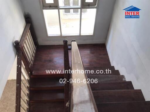 Wooden staircase with handrail leading to large window