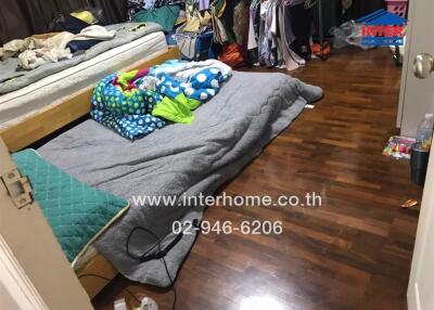 Messy bedroom with cluttered clothing and bedding on the floor