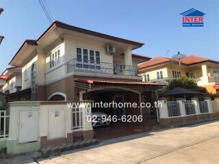 Exterior view of a two-story residential house with balcony and carport