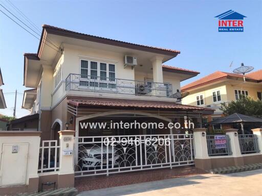 Exterior view of a two-story residential house with balcony and gated entrance