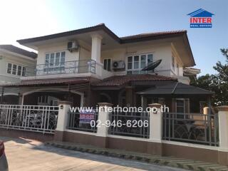 Exterior view of a large two-story house with balcony and gated driveway