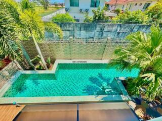 Aerial view of a beautiful residential outdoor swimming pool surrounded by lush greenery