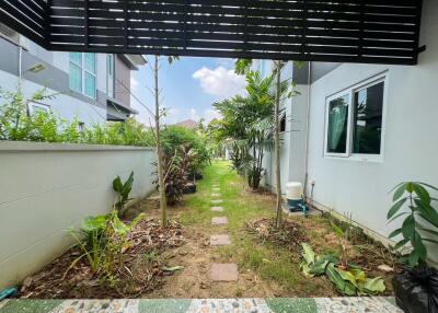 Spacious garden area with walkway and lush greenery next to a residential building