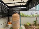 Covered patio space with water storage tank and garden