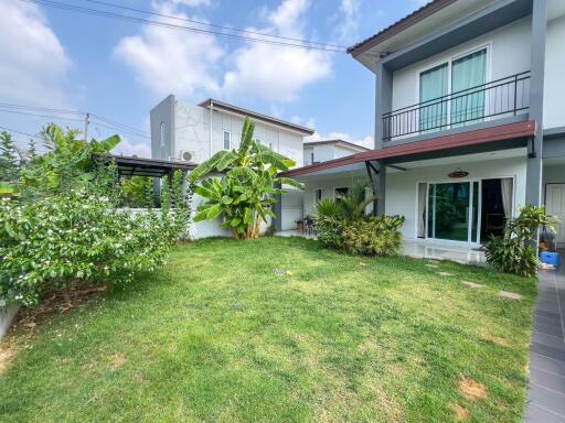 Spacious backyard of a modern two-story house with lush green lawn and garden