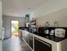 Modern kitchen with sleek cabinets and appliances leading to a bright patio