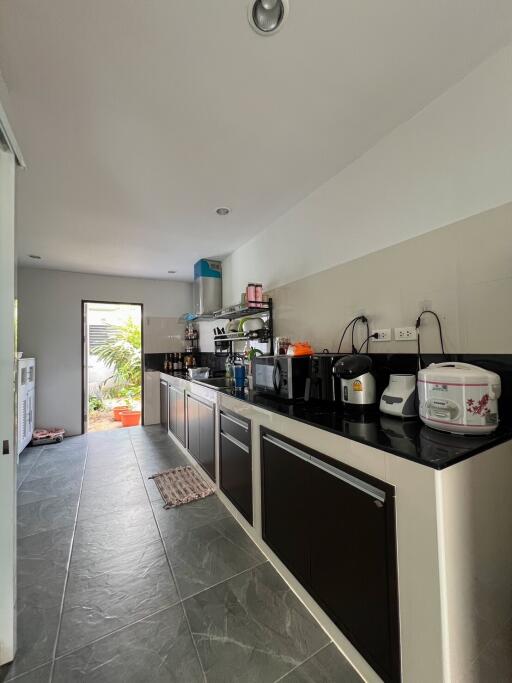 Modern kitchen with sleek cabinets and appliances leading to a bright patio