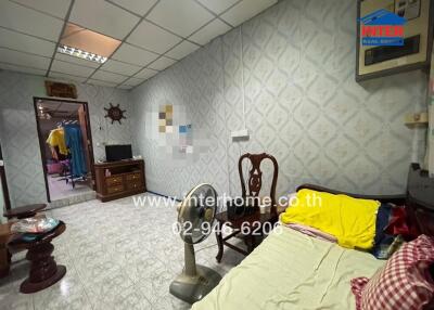Cluttered bedroom with patterned wallpaper and various furniture pieces