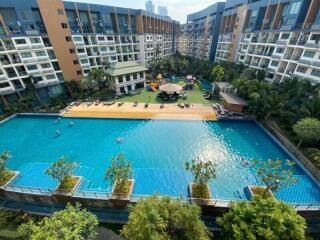 Aerial view of a luxurious residential building complex with a large swimming pool and lush greenery