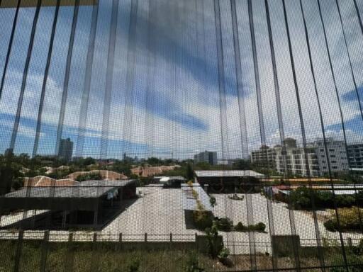 Urban view through a window screen showing surrounding buildings and partially clouded sky