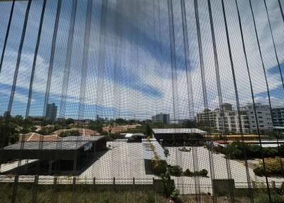 Urban view through a window screen showing surrounding buildings and partially clouded sky