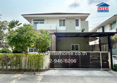 Modern two-story residential house with gated entrance and landscaped front yard