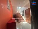 Bright hallway with red walls and staircase leading to the upper floor