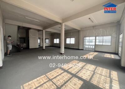 Spacious empty commercial space with numerous windows and a person inspecting