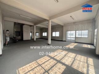 Spacious empty commercial space with numerous windows and a person inspecting
