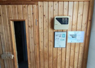 Interior view of a wooden sauna with entrance door and control panel