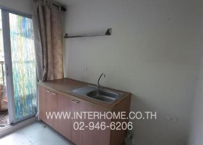 Small kitchen with sink, cabinets, and a window with curtains