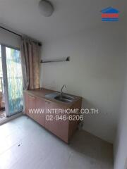 Small kitchen with sink, cabinets, and a window with curtains