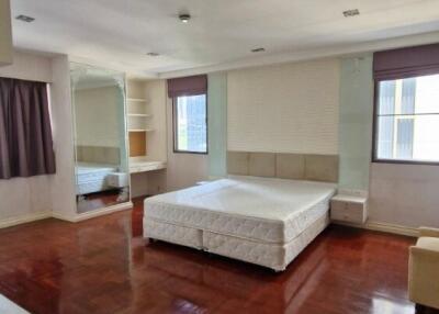 Spacious bedroom with large windows and hardwood floors