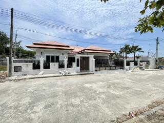 Modern single-story house with large front yard and gated entrance