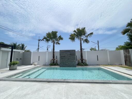 Spacious outdoor pool area with palm trees and a modern water feature