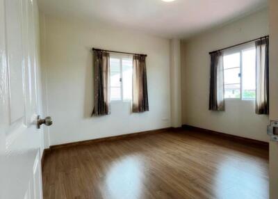 Spacious bedroom with hardwood floors and double windows