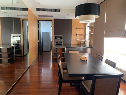 Modern kitchen with integrated dining area featuring wooden floors and contemporary appliances