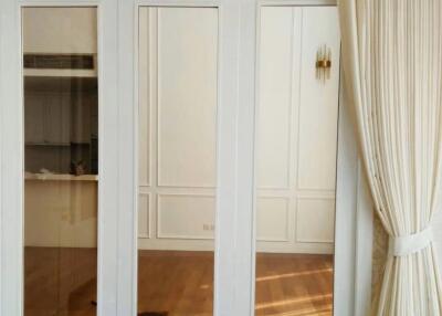 Elegant bedroom with large mirrored wardrobe and hardwood floors