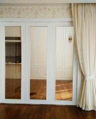 Elegant bedroom with large mirrored wardrobe and hardwood floors