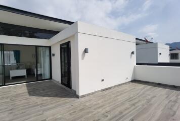 Modern exterior view of a house with large sliding doors and wooden decking