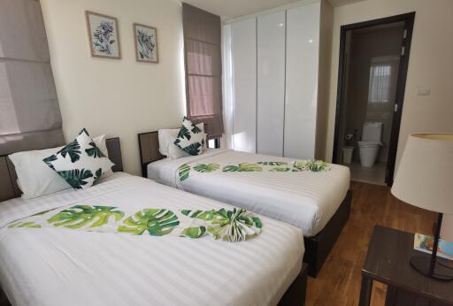 Bright and modern twin bedroom with tropical themed bedding and en-suite bathroom