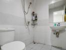 Modern white tiled bathroom with toilet, shower, and sink