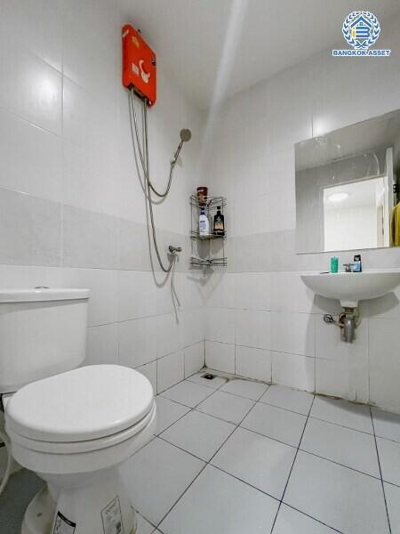 Modern white tiled bathroom with toilet, shower, and sink