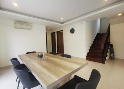 Spacious dining area with large table, chairs, and staircase leading upstairs