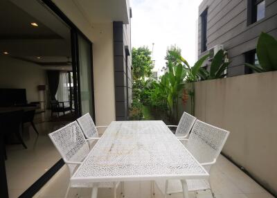 Modern patio area with white outdoor dining set and lush greenery