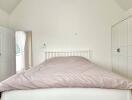 Bright and airy attic bedroom with minimalist design featuring a large bed and plush shaggy rug