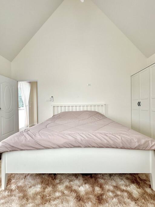 Bright and airy attic bedroom with minimalist design featuring a large bed and plush shaggy rug