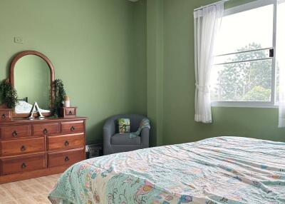 Spacious bedroom with green walls and large window