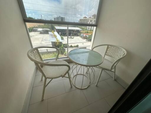 Small balcony with a round glass table and two chairs overlooking a city view