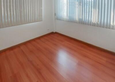 Empty bedroom with polished wooden floor and sheer curtains