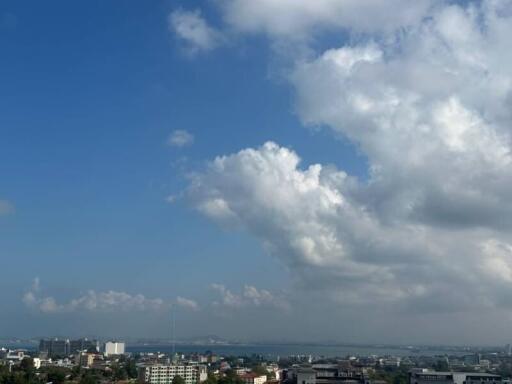 Panoramic view of a city skyline under a clear blue sky with fluffy clouds