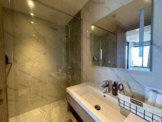 Modern bathroom with marble finish and well-lit mirror