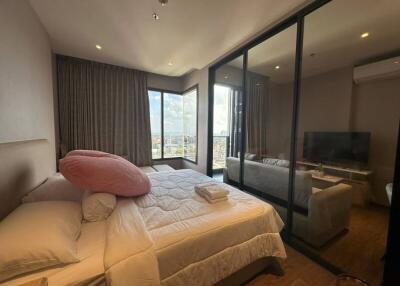 Modern bedroom with large windows overlooking the city and a connected living area