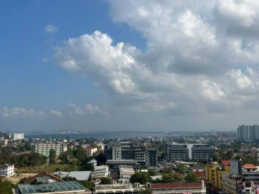 Apartment view displaying a panoramic cityscape under a blue sky with cumulus clouds