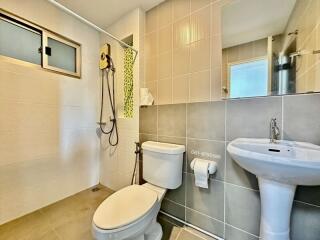 Modern bathroom with wall-mounted sink, shower, and toilet