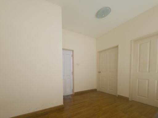 Spacious and empty bedroom with natural wooden flooring and white walls