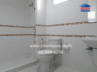 White modern bathroom with decorative tile, toilet, and open shower area
